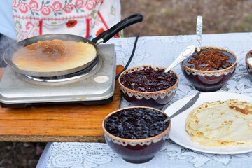 Pancakes cooked outdoors, jam in bowls as filling for pancakes, street food