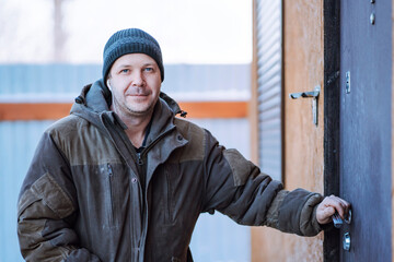 Worker in a jacket with a hood and a woolen knitted hat at the workplace