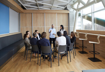 Business trainers old man and young woman conduct training in office for group of people. Training aimed at improving the efficiency of office stuff in the company. Professional development concept.