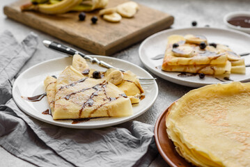 Delicious fresh baked pancakes with honey and fruits on a concrete background