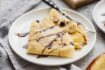 Delicious fresh baked pancakes with honey and fruits on a concrete background