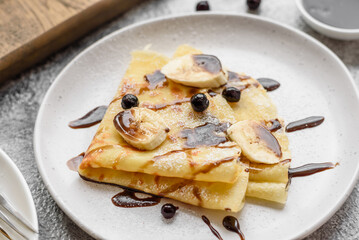 Delicious fresh baked pancakes with honey and fruits on a concrete background