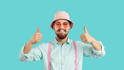 Bearded mustached man wearing pink bucket hat, cool sun shades, shirt and suspenders smiles, shows...
