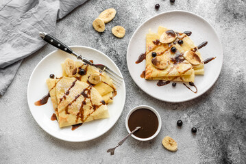 Delicious fresh baked pancakes with honey and fruits on a concrete background
