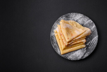 Delicious fresh baked pancakes with honey and fruits on a concrete background