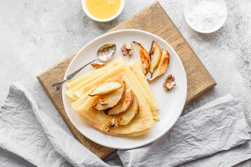 Delicious fresh baked pancakes with honey and fruits on a concrete background