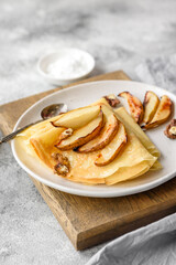 Delicious fresh baked pancakes with honey and fruits on a concrete background