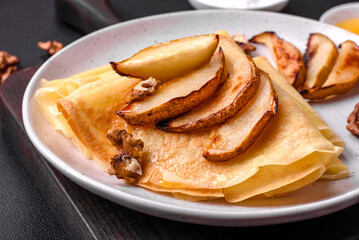 Delicious fresh baked pancakes with honey and fruits on a concrete background