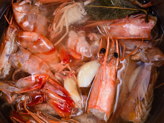 top view of heads and shells of shrimp in broth boiled with garlic and pepper close up