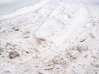 Obraz premium snowdrifts in ruts on surface of urban road in winter