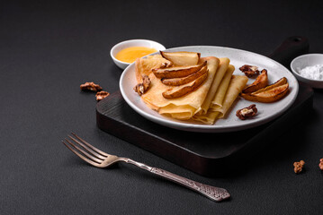 Delicious fresh baked pancakes with honey and fruits on a concrete background