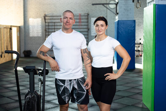 Sports couple in white t-shirts in a crossfit gym. Mock-up.