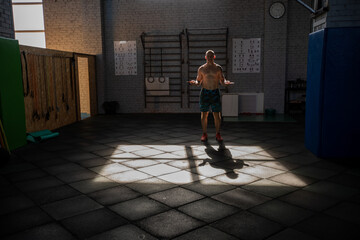 Fototapeta na wymiar Athletic man performs jumping rope in crossfit gym.