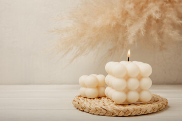 Fototapeta na wymiar Bubble candle on a textured wooden table. Trendy soy candle. Eco product. Interior decor with handmade burning candle. Side view. Close-up. Place for text.