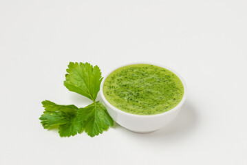 Celery or parsley  green sauce in a white ceramic bowl on a white background isolated
