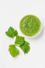 Celery or parsley green sauce in a white ceramic bowl on a white background isolated top view