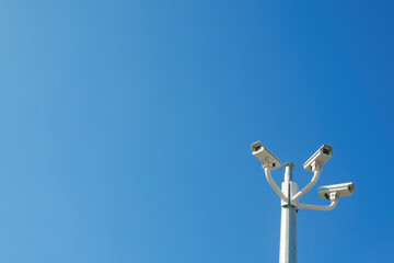 Three CCTV surveillance cameras against blue sky