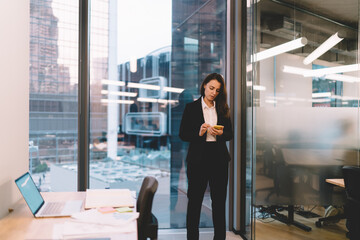 Businesswoman using smartphone in office with panoramic window