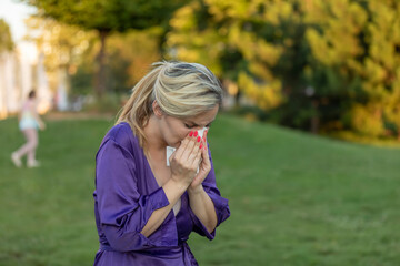Cold and flu. Young attractive woman, caught a cold,  wipes her nose with a napkin.