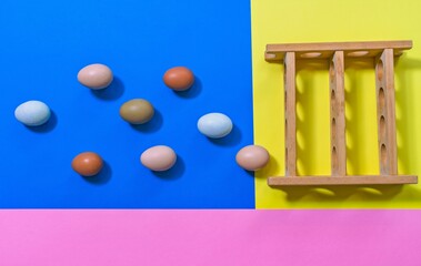 Flat lay eggs on a bright background, eggs appear to be falling into a rack, illusion of a game. Playful egg concept with strong coloured backdrop. copy space.