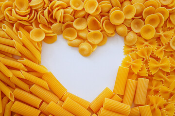 Framing for heart-shaped copy space made with various types of pasta on a white background