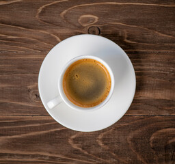 Espresso in a white cup on a wooden brown table