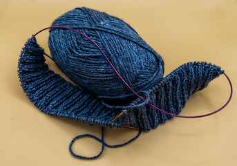 blue yarn a knitting needle and a started needlework