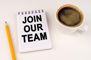 On a white surface, a cup of coffee, a pencil and a notepad with the inscription - join our team
