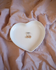 Pendientes dorados en forma de corazón dentro de un joyero en forma de corazón sobre un fondo rosa