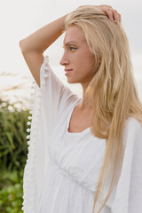 Naklejka premium Lovely cutie smiling woman with long hair looking to the ocean with happy smile on the shore of ocean. Recreation concept, vacation, trip.