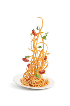 Pasta with tomatoes and basil falling into a plate, levitation.