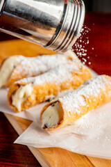 Fototapeta na wymiar Cannoli. Classic traditional Italian dessert. Italian pastries made with tube-shaped shells of fried pastry dough filled with a sweet, creamy ricotta filling. Traditional Sicilian dessert.