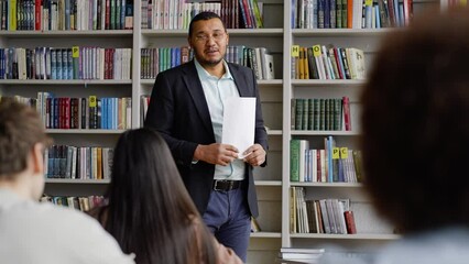 Inspired positive African American young professor reading lecture to a group of teenage students