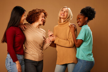 Multicultural girls with pure natural skin posing in studio and looking at the camera isolated on brown background.