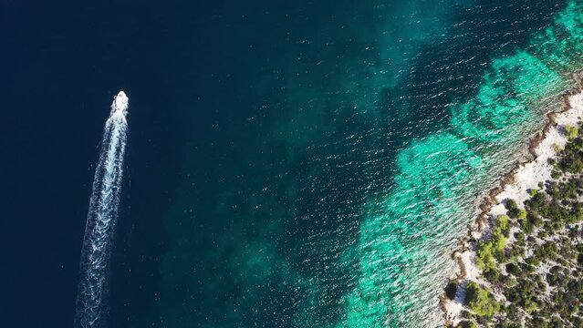4K lonely motor boat moving near the turquoise Adriatic Sea coast waves. Aerial coastal top view 4K footage.
