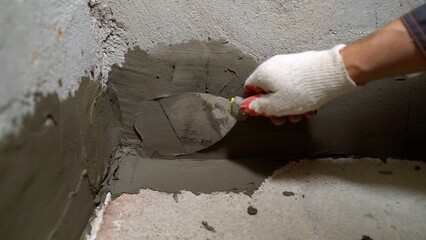 Repairing concrete walls close-up view of the hands of the master. Repair work with a spatula and...