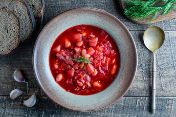 Ukrainian national dish red borsch in a ceramic plate on a wooden background. Beetroot soup is a national dish in Ukraine, top view
