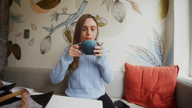Young woman relaxing at a caf&eacute;, enjoying a Chai Latte.