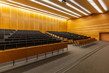 Interior of big conference hall full of gray folding chairs and wooden walls