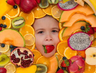 Strawberry in child mouth. Frutit and child face close up. Top view of child face with mix fruit. Fruits set near kids face.