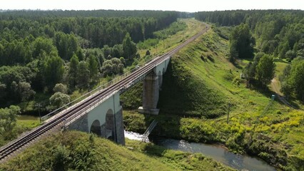 Aerial view of a train track bridge, railway bridge over the River Rauna, Latvia. Highest railway structure in Baltic countries. Endless railway without train. Empty straight single-way track.