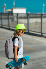Childhood. Cute child with skateboard on street background. Summer outdoor sport. Funny kid boy,...