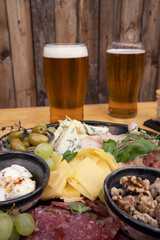 Closeup view of a dish with sliced salami, cheese, blue cheese, focaccia bread, italian boconccinos, walnuts, ham, cured ham and green olives on the wooden table. 