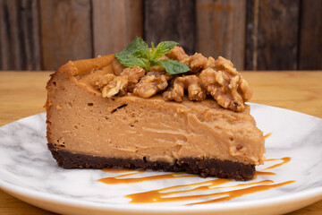 Desserts. Closeup view of a slice of dulce de leche cheesecake with nuts and caramel sauce.