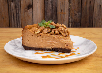 Desserts. Closeup view of a slice of dulce de leche cheesecake with nuts and caramel sauce.