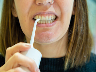Naklejka premium Healthy Oral Hygiene: Young woman Using domestic dental water flosser 