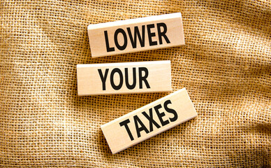 Lower your taxes symbol. Concept words Lower your taxes on wooden blocks on a beautiful canvas table canvas background. Business tax lower your taxes concept. Copy space.