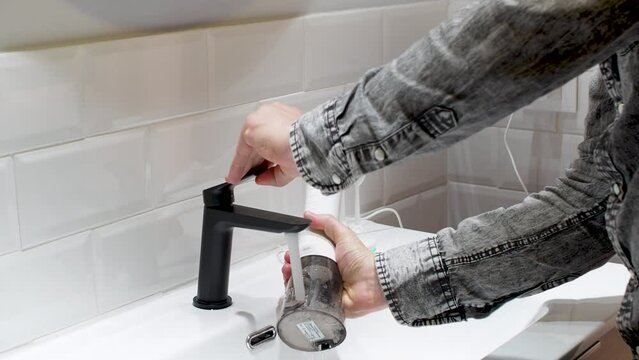 Effortless Oral Health: man Filling Water Flosser Tank at Bathroom Basin 