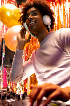 Vertical image of smiling african american dj in headphones playing music at a nightclub