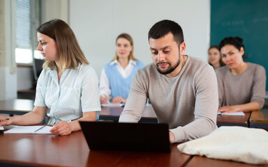 Guy student, studying at the same desk with a girl fellow student in a university auditorium with a...